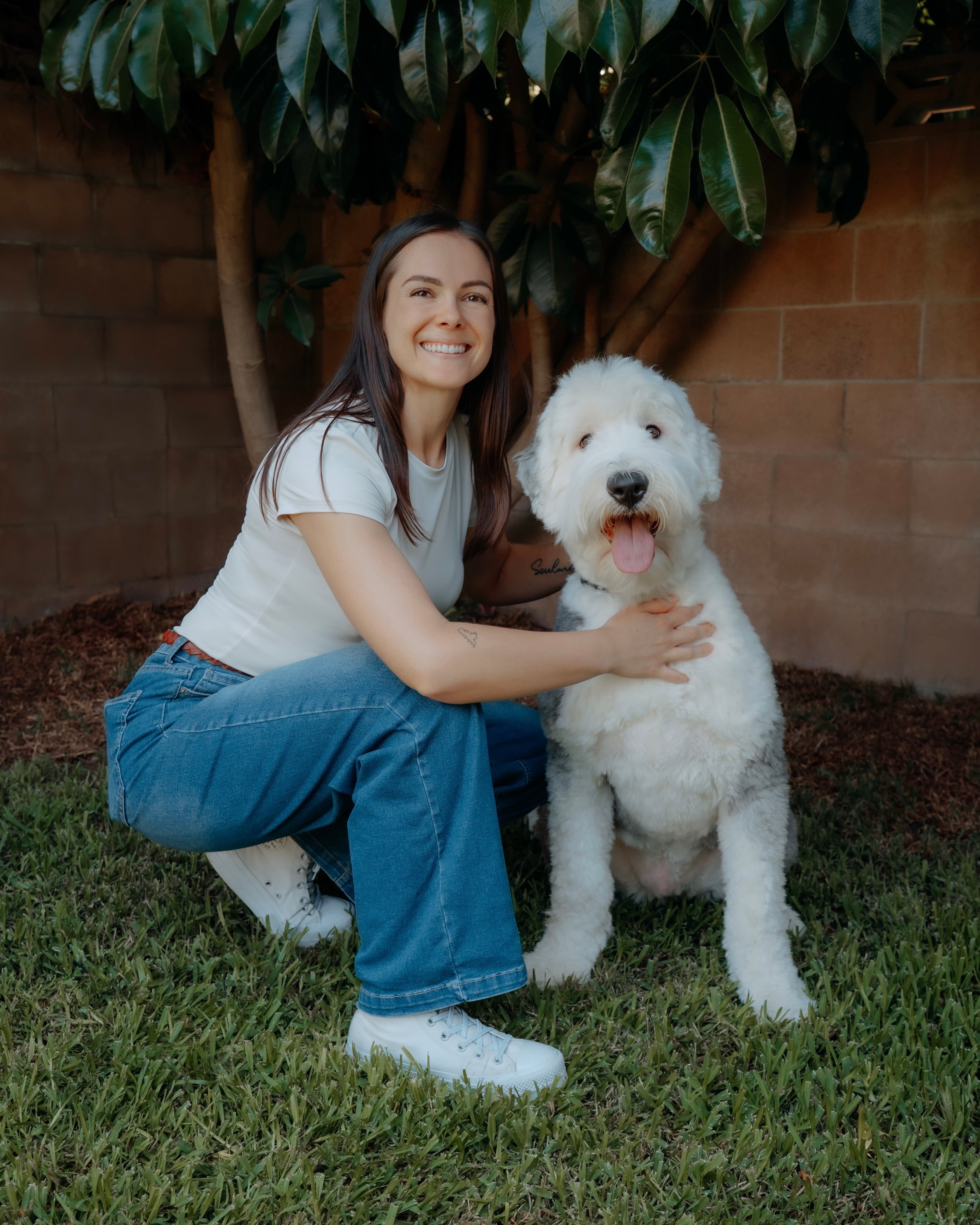 Kendall kneeling beside a white dog