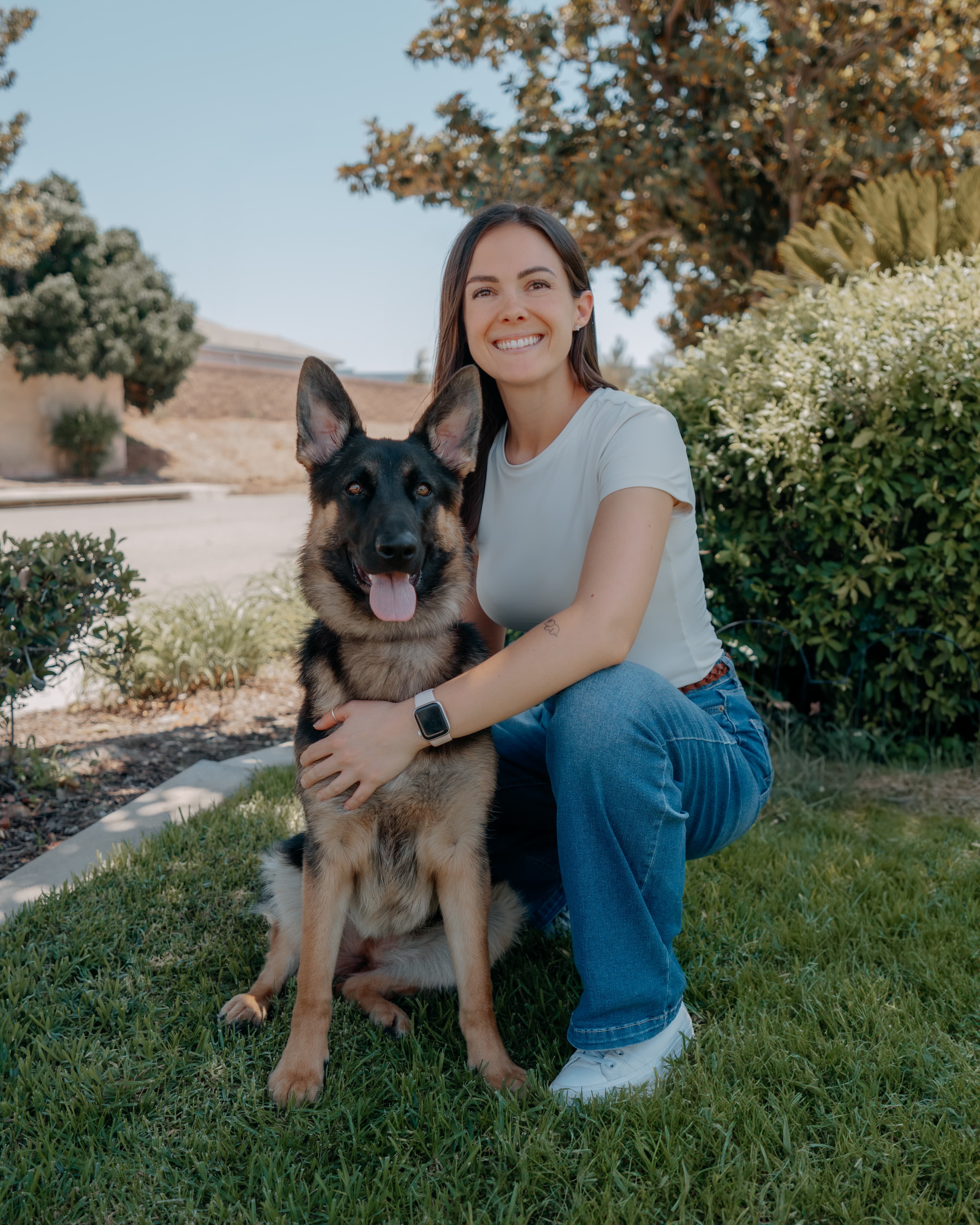 Kendall kneeling beside a German shepherd